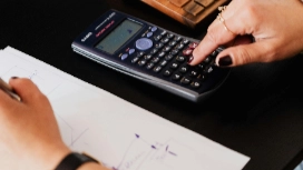 Hand using calculator over accounting notes – learn AI in Accounting short course online with OHSC today