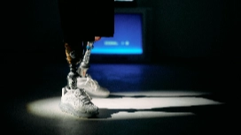 Futuristic prosthetic legs in sneakers under spotlight, symbolising AI-driven innovation in fashion design.