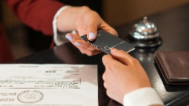 Hotel receptionist handing a key card to a guest, representing digital check-in systems and AI-enhanced guest service in hospitality management.