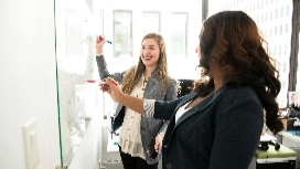 Two professionals collaborating at a whiteboard, reflecting AI-driven leadership skills in OHSC short course.