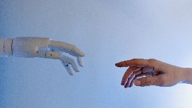 Human hand reaching toward a robotic hand, symbolising AI prompt optimisation and business-focused prompt engineering skills