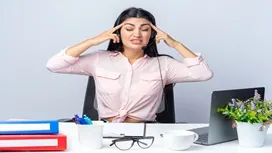 A woman sitting at a desk with her fingers on her temples, illustrating stress relief techniques and AI-supported stress management skills.