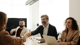 Professionals in a calm meeting setting with a handshake, symbolizing communication, conflict resolution and emotional control in anger management courses.