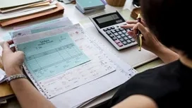 Accountant reviewing balance sheets and financial records with a calculator, representing essential skills in balancing a balance sheet