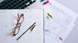 Notebook with glasses, pen and financial statements on desk – learn balance sheet preparation online with OHSC