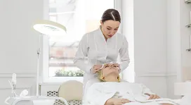 A beauty therapist performing a facial treatment on a client in a modern salon, representing beauty therapy training online.