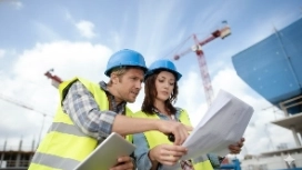 Construction professionals reviewing plans together, illustrating workplace relationships, teamwork and conflict resolution skills