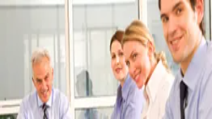 Business professionals sitting together and smiling during a meeting, illustrating teamwork and communication skills in business communication training.