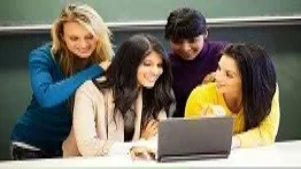 Students gathered around a laptop collaborating on ideas, representing teamwork, innovation, and business development training at Level 5.