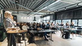 Professional speaker addressing a group of adult learners during a business training session, illustrating concepts taught in business ethics courses.