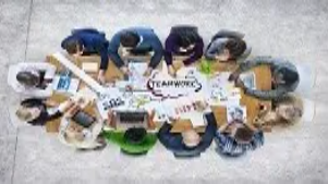 Team members gathered around a table reviewing charts and planning strategies, representing collaboration and improvement skills for Business Improvement Level 3.