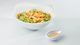 Fresh chicken salad served in a clean white bowl with dressing, representing safe food preparation and hygiene practices taught in food hygiene courses.