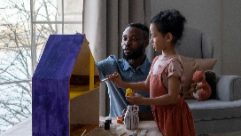 Caregiver reading with a young child at home, supporting early learning and growth – child care and development course