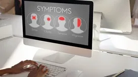 Person reviewing illustrated symptom indicators for stress-related conditions on a computer screen, representing Complex PTSD signs and symptoms training.
