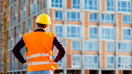 A construction professional in safety gear observing a building project, representing foundational planning and supervision skills in Construction Management QLS Level 2.