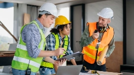 Construction managers reviewing project plans on-site with safety gear, representing OHSC Construction Management courses online.