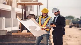 Two construction professionals reviewing blueprints on-site, demonstrating planning and supervisory skills taught in the Construction Site Management QLS Level 4 Diploma.