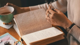 Learner writing in a notebook with coffee, inspiring creativity for OHSC Creative Writing free short course online.