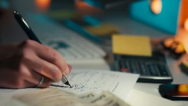 Person reviewing documents and making analytical notes with a pen, symbolizing evaluation, reasoning and analysis taught in critical thinking courses.