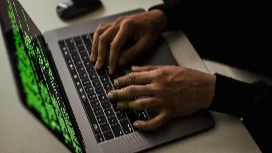 Person typing on a laptop displaying green code, symbolizing online security, cyber threats and key protection skills taught in cybersecurity courses.