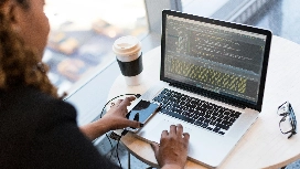 Professional working on a laptop displaying code, symbolizing digital protection, data security and essential cybersecurity practices for businesses.
