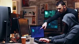 Two cybersecurity analysts review suspicious activity on multiple screens, illustrating AI-powered techniques for detecting and preventing cyber threats.