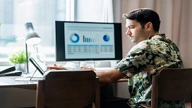 Person working at a desk with charts and analytics displayed on a computer screen, representing online data analysis learning and skills development.