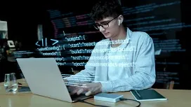 Young man working on a laptop with code projected around him, illustrating Python-based data wrangling and preprocessing techniques.