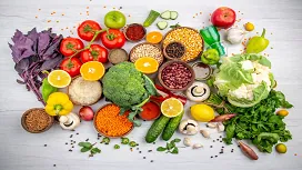 A colorful selection of fresh vegetables, fruits, grains, and legumes displayed on a table, representing core concepts in diet and nutrition education.