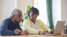 Teaching assistant supporting adult learner with laptop – dyslexia awareness short course online with OHSC