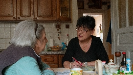 Caregiver discussing daily support needs with an older adult at home, demonstrating elderly care and assistance skills
