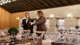 Event managers reviewing a decorated venue with elegant table settings and lighting, representing the Level 4 Diploma in Event Management.