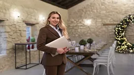 Professional event manager standing in a decorated venue with formal table settings, representing the advanced Level 7 Diploma in Event Management.