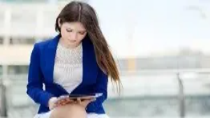 A professional woman reviewing information on a tablet, representing advanced administrative skills for the Executive PA Diploma Level 6.