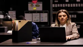 Woman reviewing financial records on a laptop in an office setting, representing investigation and analysis in forensic accounting Level 3