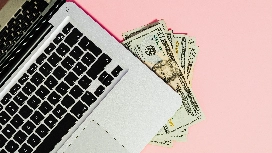 Laptop with cash earnings beside it, representing freelance work platforms and online income strategies for remote professionals