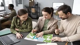 Three professionals reviewing a global project map together, representing planning, coordination, and international project management strategies.