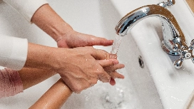 Caregiver helping a child wash hands properly, demonstrating health and hygiene practices in caregiving
