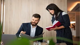 Two hospitality professionals reviewing documents in an office setting, representing leadership, planning, and strategic skills in advanced hotel management training.