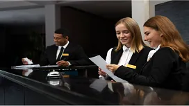 Hotel front-desk staff reviewing documents together, highlighting customer service, teamwork, and entry-level skills taught in hotel management courses.
