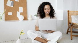 Professional woman working on a laptop in a bright room, symbolizing modern HR practices, digital tools and people management skills taught in HR management courses.