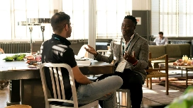 Two colleagues in a professional setting talking and gesturing, illustrating interpersonal skills training online.