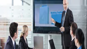 A professional trainer presenting to a small group in a meeting room, illustrating foundational communication and delivery skills taught in Level 3 trainer courses.