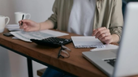 Person reviewing notes beside a calculator and laptop – learn key financial reports online with OHSC short course