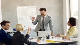Confident business leader presenting strategy to a team during a meeting, representing advanced leadership and management principles taught in the Level 6 diploma.