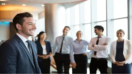 Confident business leader standing in front of a smiling team, representing teamwork, communication, and leadership skills taught in the Level 3 Leadership and Team Skills course.