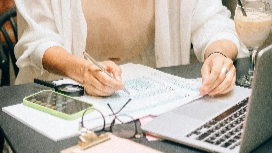 Accounting student reviewing financial notes beside a laptop and calculator, representing diploma accounting finance Level 4 studies.