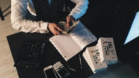 Accounting professional counting cash beside financial records and calculator, representing diploma of accounting online Level 5 studies.