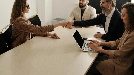 Business professionals shaking hands during a meeting, representing collaboration and leadership in a Level 5 business enterprise course.