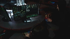 Cyber security professionals monitoring encrypted data on multiple screens, representing advanced skills taught in a Level 5 cyber security certificate program.